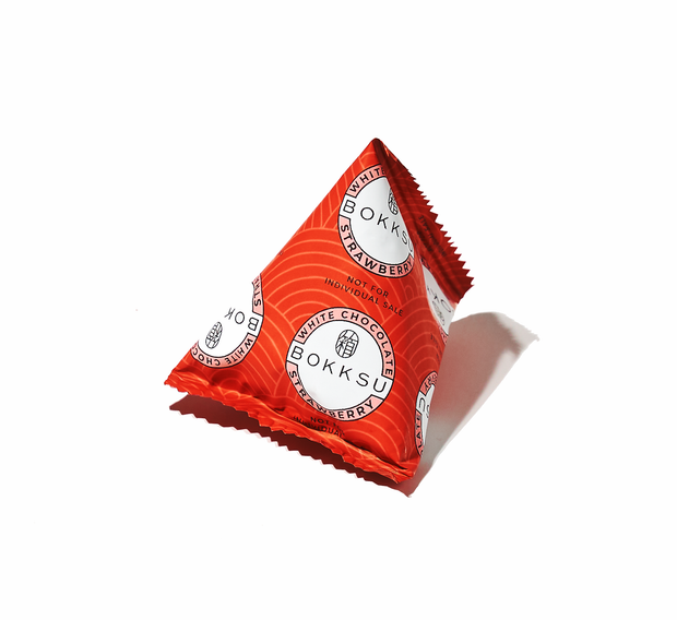 A Bokksu "Gift: White Strawberry" snack, featuring a red triangular box, elegantly displays the fusion of Japanese snacks and strawberry chocolate on a pristine white background.