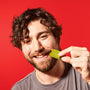 A smiling man with curly hair, on a red background, about to eat a piece of Nestle Japan& thumbnail 3
