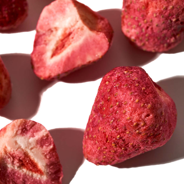 Close-up of freeze-dried strawberries, some whole and some sliced in half, on a white background—reminiscent of the Bokksu White Strawberry 6-Piece Box (3-Pack), these delightful Japanese snacks burst with the essence of chocolate-infused strawberry goodness.