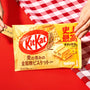 Hands holding a Nestle Japan Whole Wheat Cookie Kit Kat package with the flavor text in Japanese and English, aimed at health-conscious snackers, over a red and white checkered background. thumbnail 2