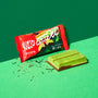 A Green Tea Double Layer Japanese Kit Kat bar by Nestle Japan with its packaging, partially unwrapped, exposing the chocolate on a green background. thumbnail 2