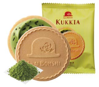 A pack of Kukkia Crepe Cookie: Matcha Chocolate from Bokksu Market highlights a crispy cookie with a hat design, alongside another cookie with green filling reminiscent of matcha chocolate, partially displayed beside a small sachet of premium green tea powder.