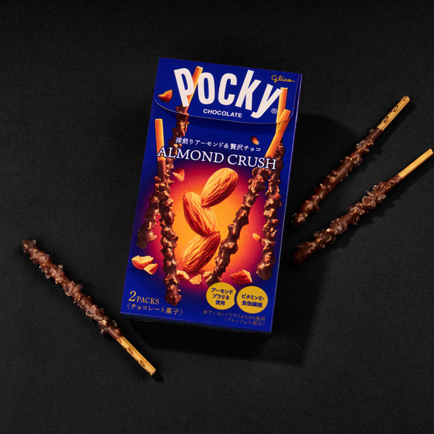 Glico Pocky: Chocolate & Almond Crush, displaying the biscuit sticks coated with chunky almond pieces and chocolate, arranged around their distinctive blue packaging. Brand: Bokksu Market; Product: Glico Pocky : Chocolate & Almond Crush.