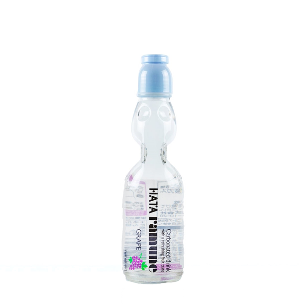 The image features a Hata Ramune Soda: Grape (6.76 oz) bottle. The packaging is transparent with purple accents, including small grape illustrations. This carbonated Japanese soda is contained in a marble-sealed glass bottle, adding a fun, interactive drinking experience. The grape flavor offers a sweet and fruity taste, making it a refreshing and nostalgic beverage. Brand: Bokksu Market; Product: Hata Ramune Soda: Grape (6.76 oz).