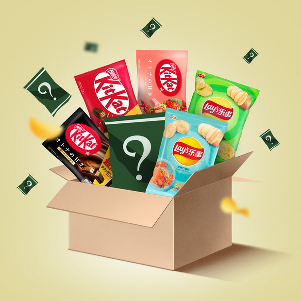 The Mystery Pack by Bokksu Market is an open box of unique Asian snacks like KitKat and Lay’s, plus green mystery packages marked with question marks.