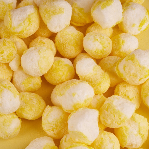 Close-up of Japanese Candy Bites Duo: White Strawberry & Sour Yuzu by Bokksu Market, featuring yellow and white treats scattered on a yellow surface.