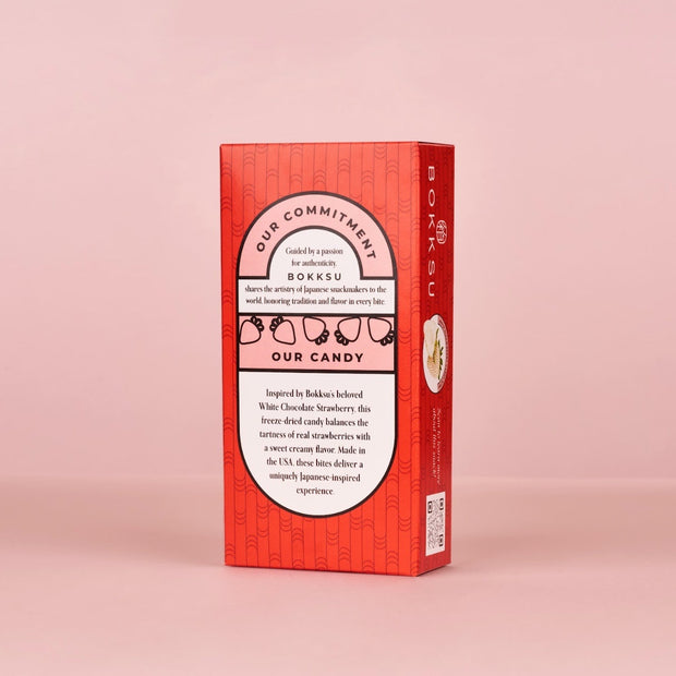A red rectangular Bokksu Market box of White Strawberry Japanese Candy Bites (4-Pack) stands upright against a light pink background, highlighting its creamy white chocolate and signature strawberry treats.