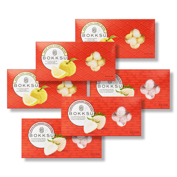 Seven red Bokksu Market boxes are shown, each featuring illustrations of citrus fruits and strawberries to highlight the Japanese Candy Bites Duo: White Strawberry & Sour Yuzu (3-Pack).