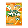 The image features a package of Uha Sakeru Gummy: Orange (7 pieces) by Uha Mikakuto, vividly showcasing its orange-flavored gummy candy with bright graphics, a peeled orange illustration, and Japanese text. The vibrant packaging highlights