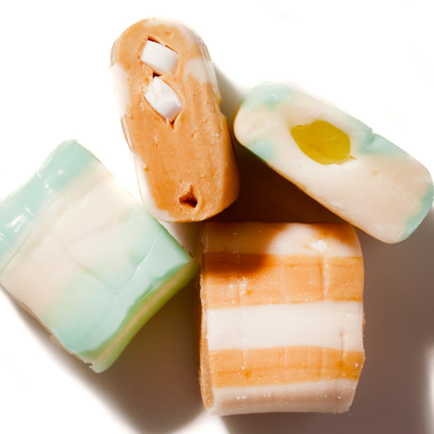 Four different types of UHA Mikakuto Puchao Gummy Candy: Ramune & Cola, including cola and chewy candy, are arranged on a white surface.