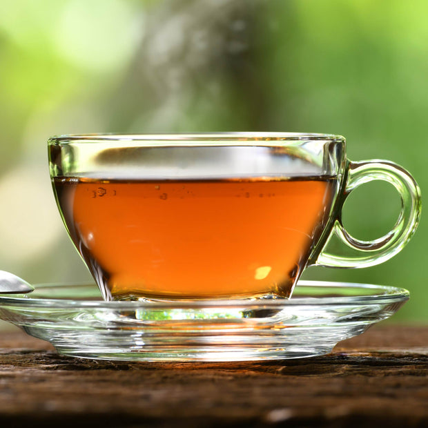 A cup of Butterfly Hong Kong Style Breakfast Tea (100 bags) with a spoon on a wooden table.