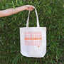 A woman holding a Bokksu Snack Tote Bag that says snacksack. thumbnail 2