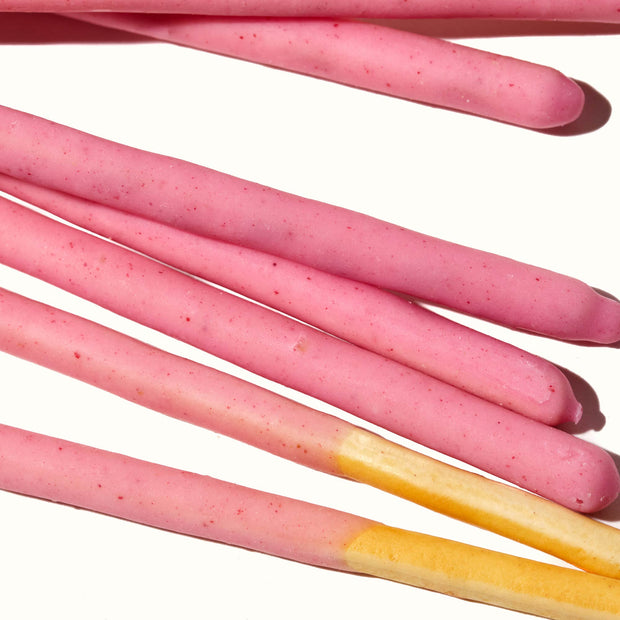 A bunch of Glico Pocky: Strawberry sticks on a white surface.