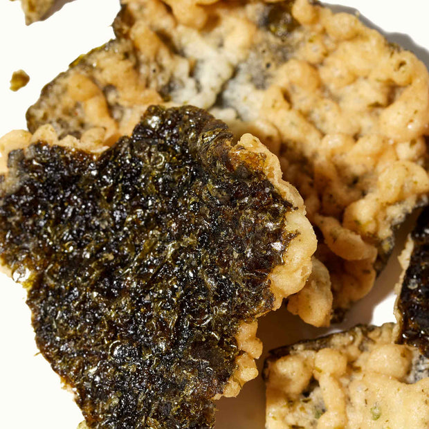 A piece of Ohgiya Noriten Seaweed Tempura Chips: Wasabi on a white plate.