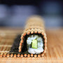A Marufuji Makisu Sushi Bamboo Rolling Mat is sitting on a wooden table. thumbnail 3