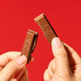 Two hands break a Nestle Japan Japanese Kit Kat: Chocolate Orange bar against a solid red backdrop, highlighting a delightful seasonal treat. thumbnail 3