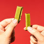 Two hands breaking a Japanese Kit Kat: Green Tea Double Layer (2-Pack) by Nestle Japan against a vibrant red background. thumbnail 3