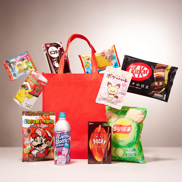 The Snack Attack Lucky Bag by Bokksu Market is a red tote filled with assorted Japanese snacks like Pocky, KitKat, Lay’s chips, Ramune soda, and other colorful seasonal treats.