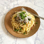 A plate of spaghetti topped with chopped green onions, grated cheese, and sliced mushrooms, enhanced with a hint of Bokksu Tinned Shirasu Anchovies with Yuzu Pepper (2-Pack) for a zesty kick, with a fork resting on the right side. thumbnail 5