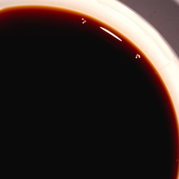 A cup of Pearl River Bridge Superior Sheng Chou Light Soy Sauce on a table.